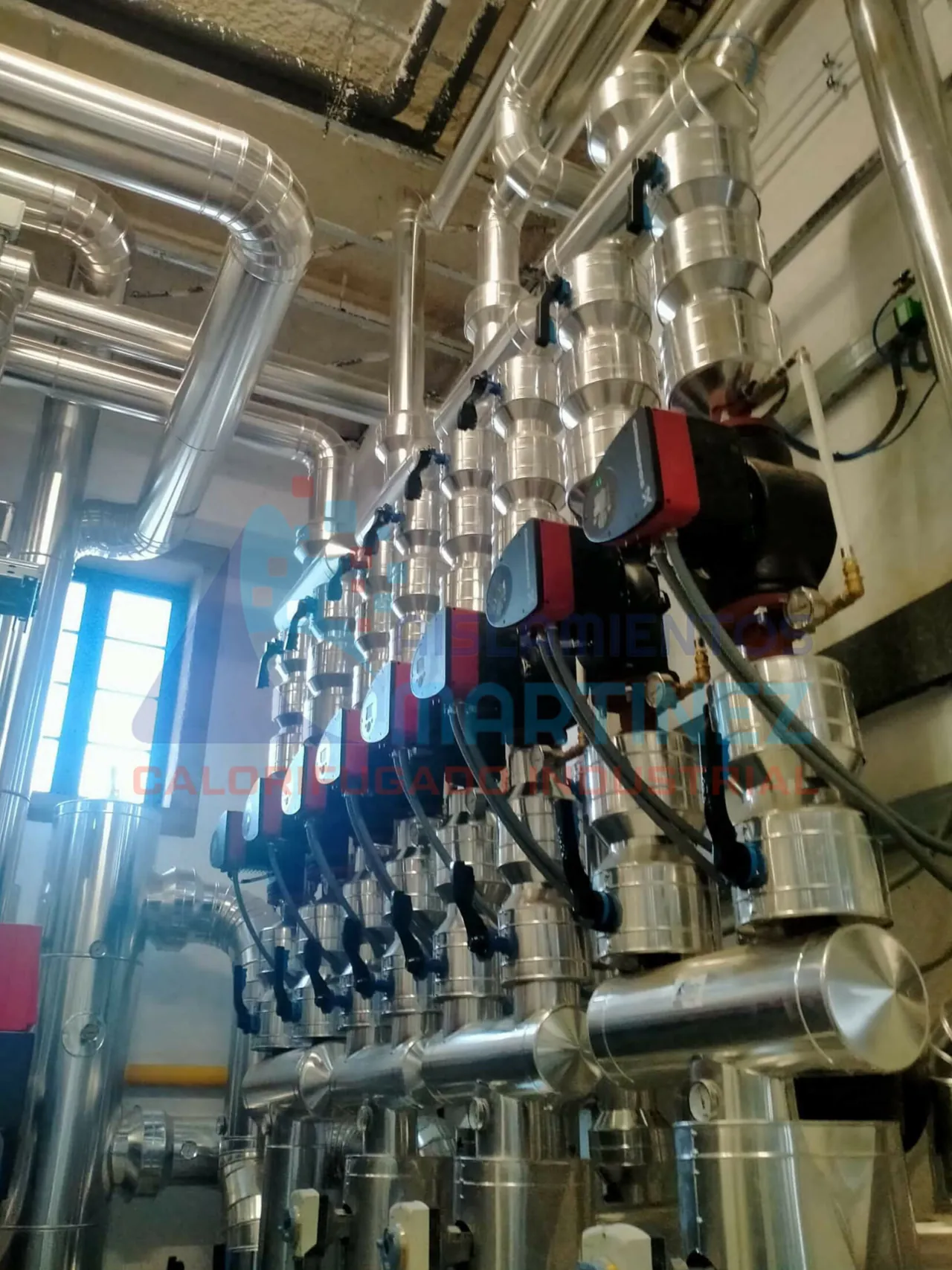 Conjunto de tuberías revestidas y conexiones en una sala de instalaciones.